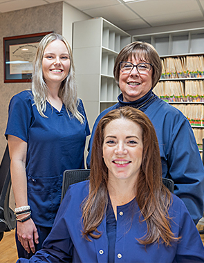 Dental team member handing pamphlet to woman from across desk