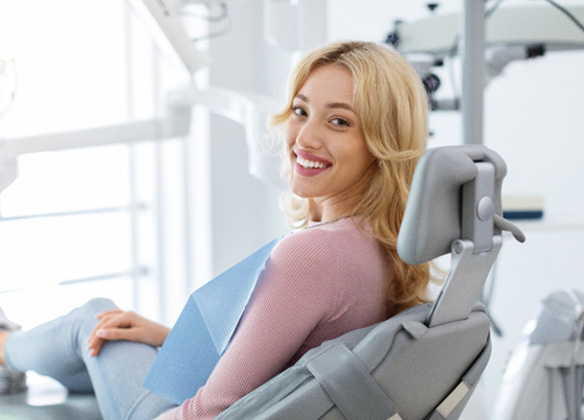Blonde haired woman sitting in dental chair smiling