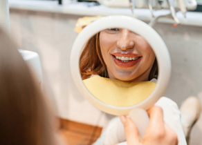 Female patient checking smile in handheld mirror