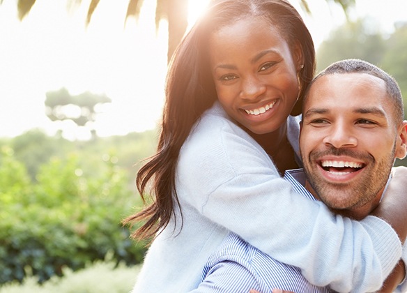 A man and woman having fun while outside and smiling after seeing their dentist near Wall Township, NJ