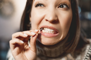 Woman squinting while using a toothpick