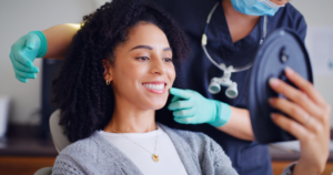 a dentist showing a woman her smile in a handheld mirror