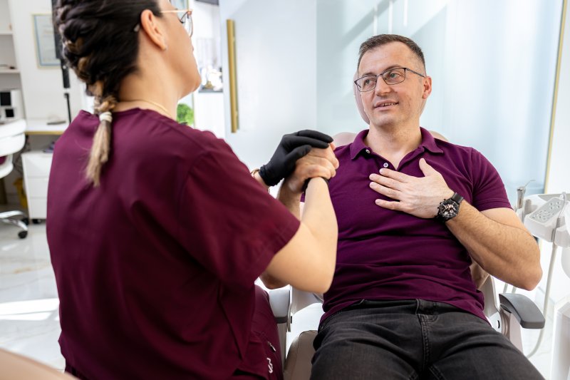 Dentist comforting patient getting dental implants
